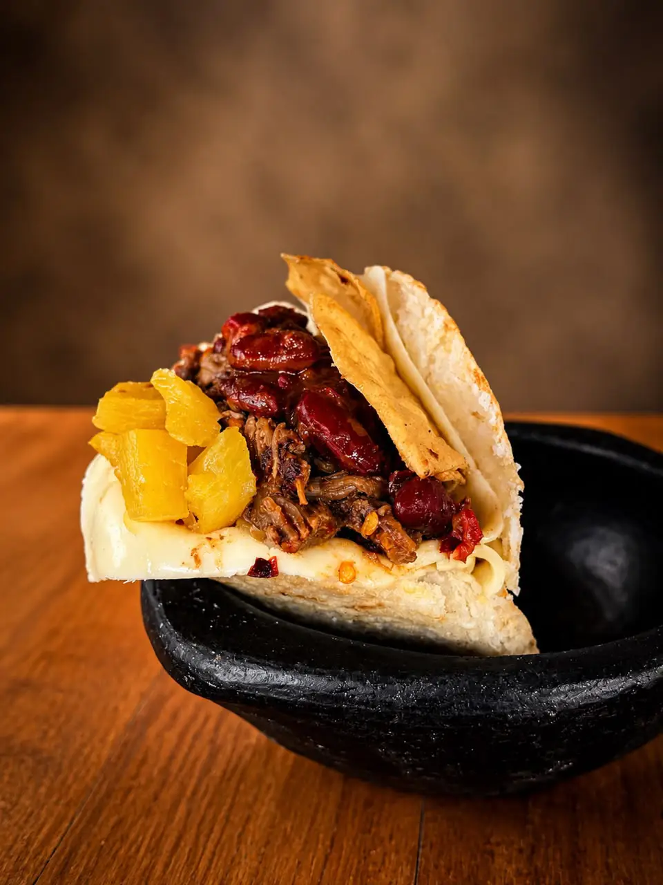 Arepa D’ Chingona con carne desmechada, chile quebrado, frijol refrito, totopos, queso y piña